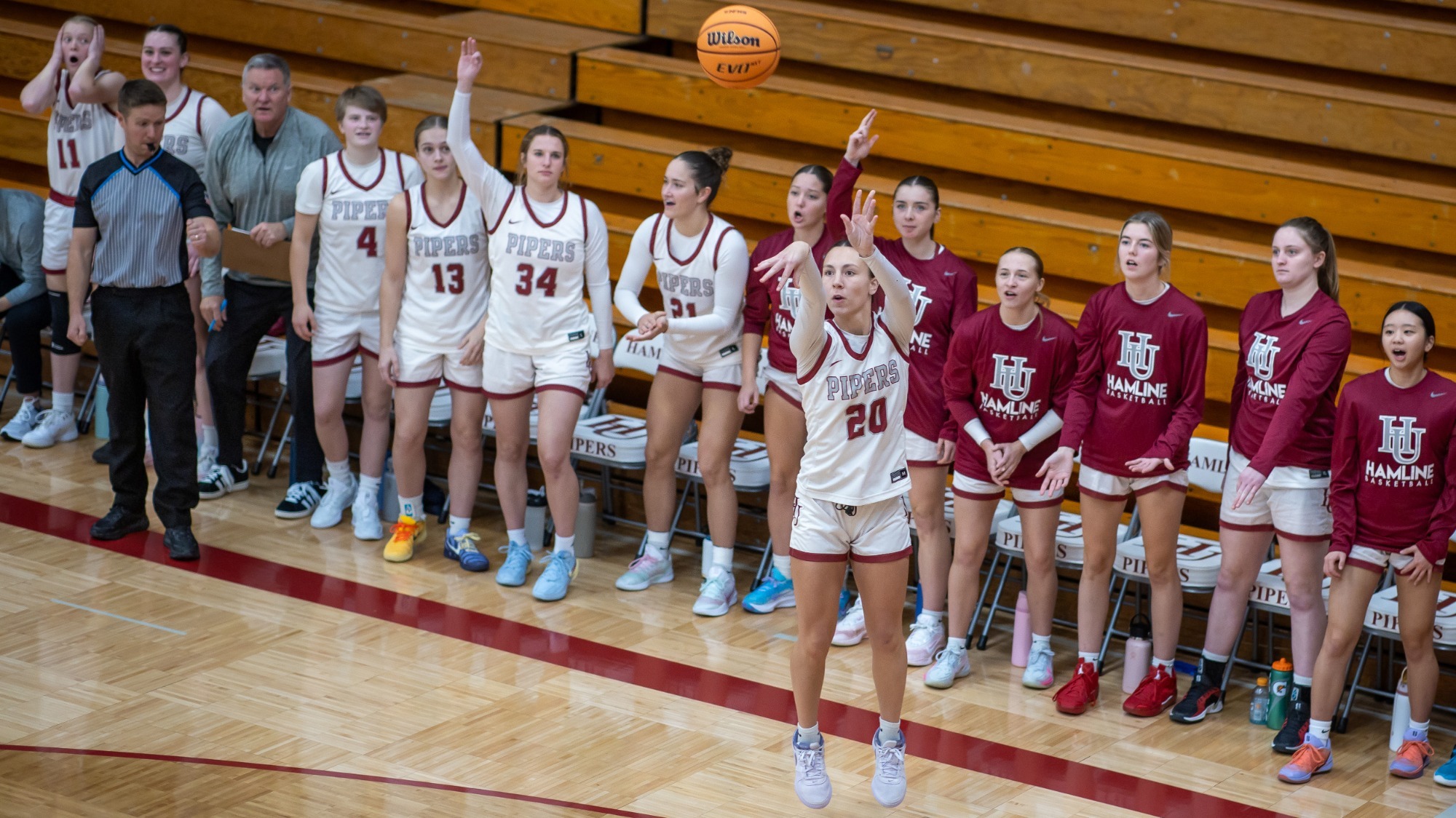 Camille Cummings shooting 3 pointer in front of home bench cheering 