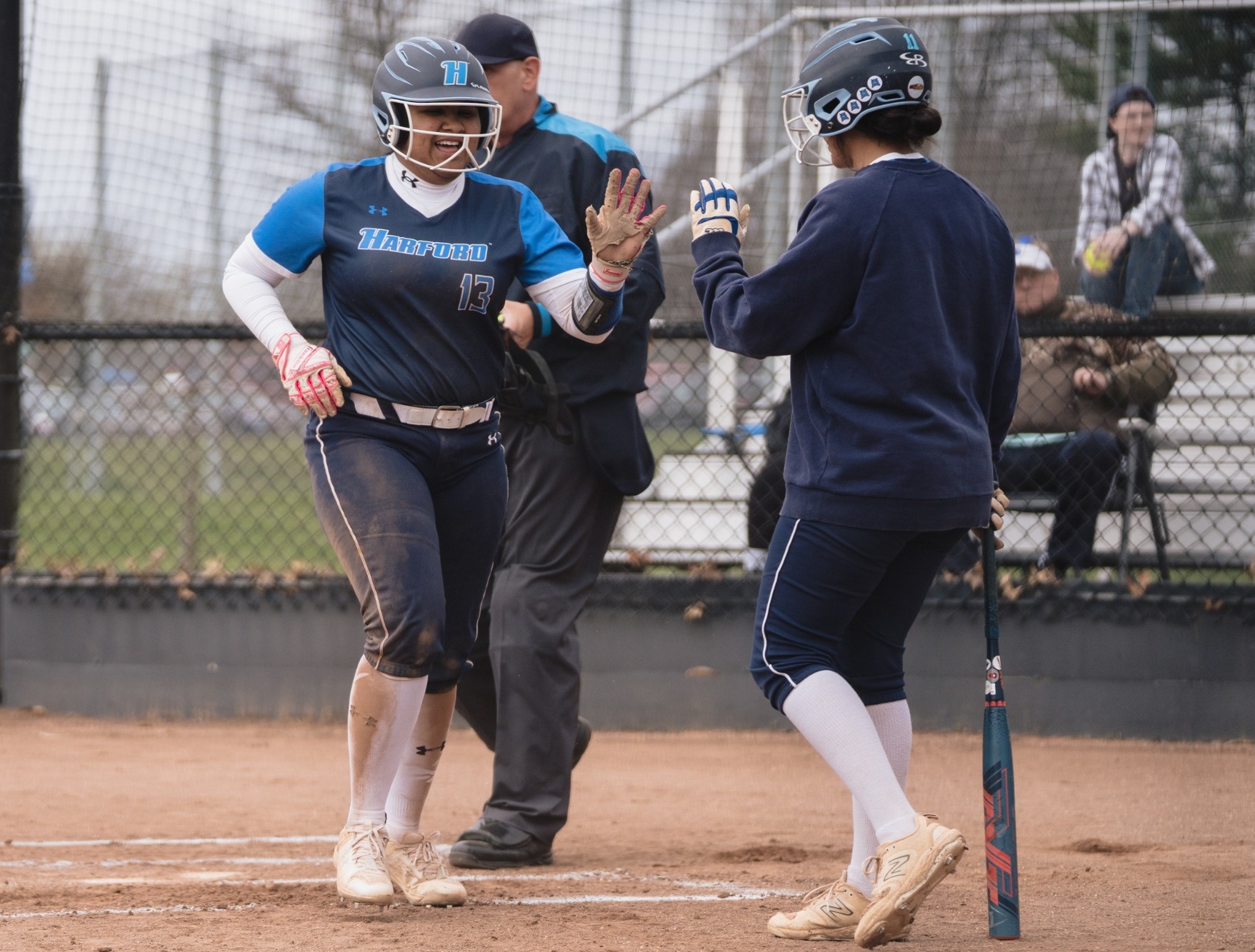 Juliet Sanchez (left) gives a high-five to teammate Arianna Blum (right) after scoring a run