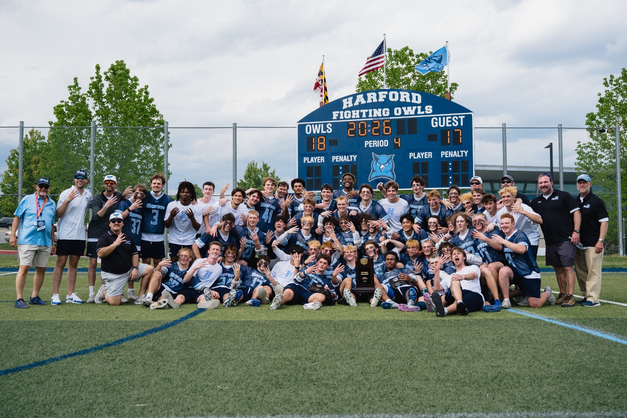 Harford Lacrosse team poses for a photo in front of the score board after winning its fourth straight national title