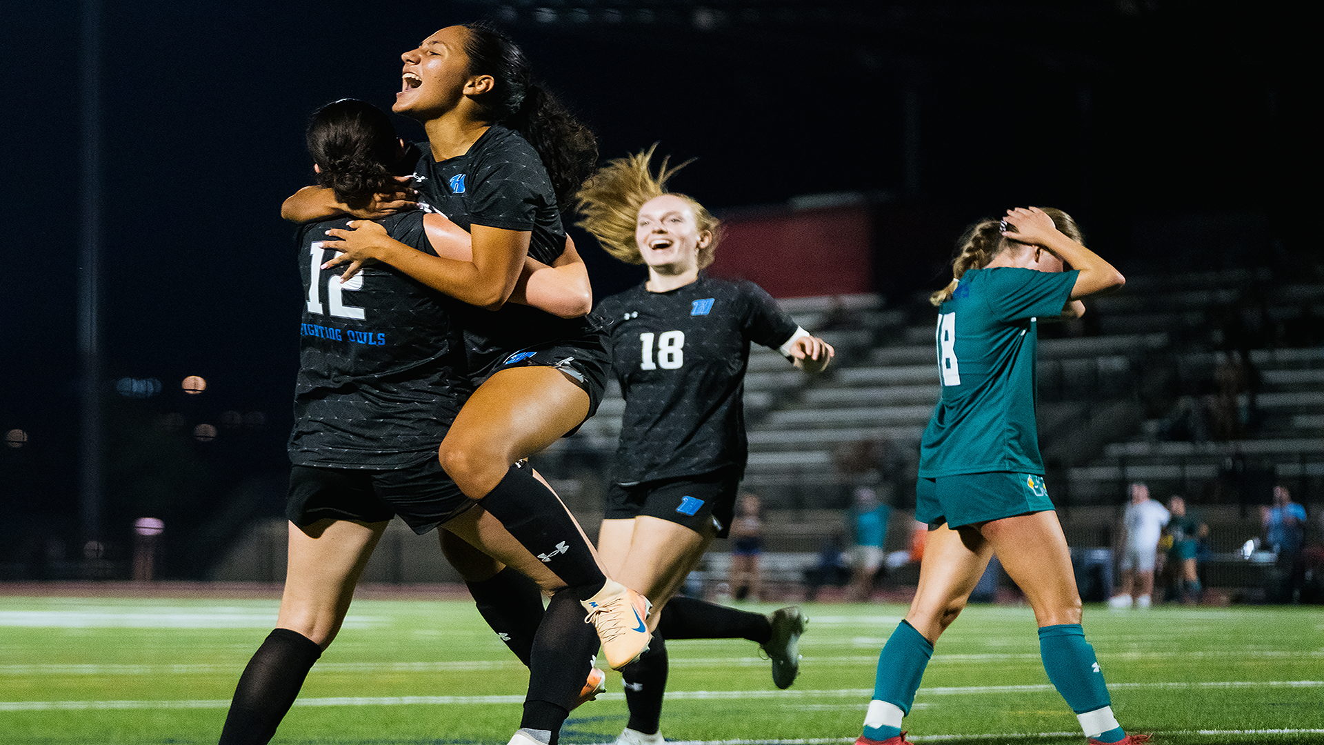 Three Harford women's soccer players celebrate scoring a goal. 