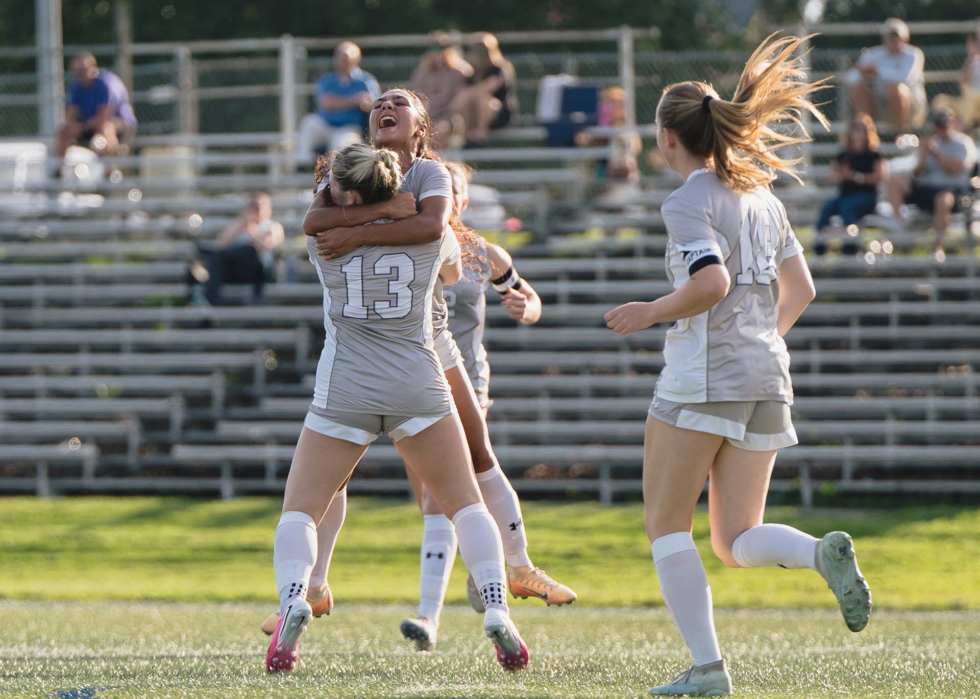 Three Harford Fighting Owls women's soccer players celebrate a goal.