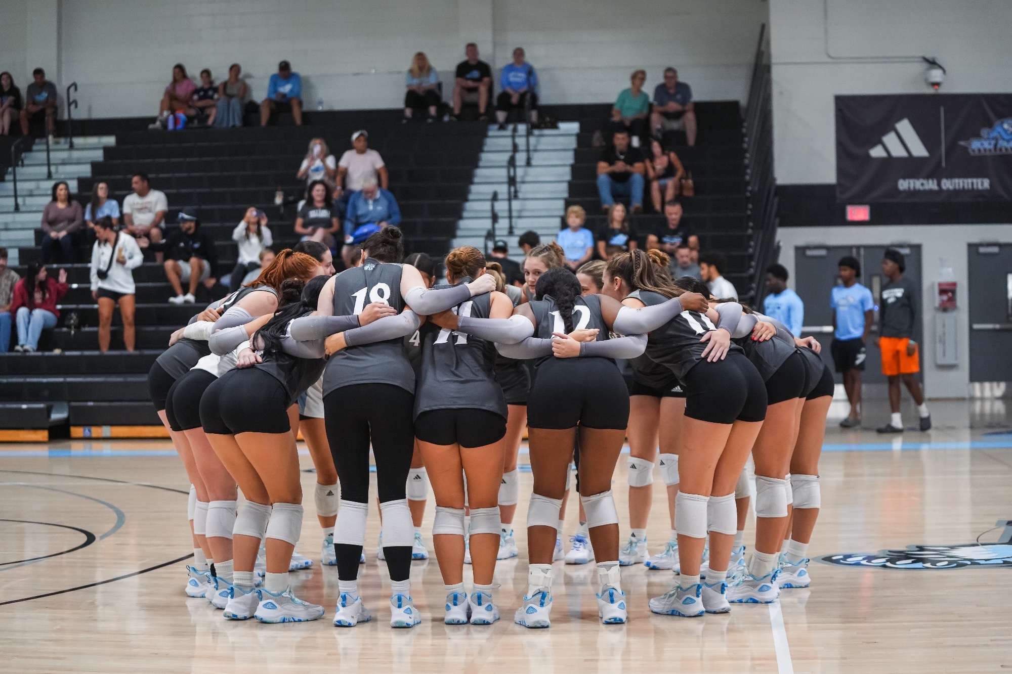 The HFU Volleyball Team huddles on the court together prior to a match