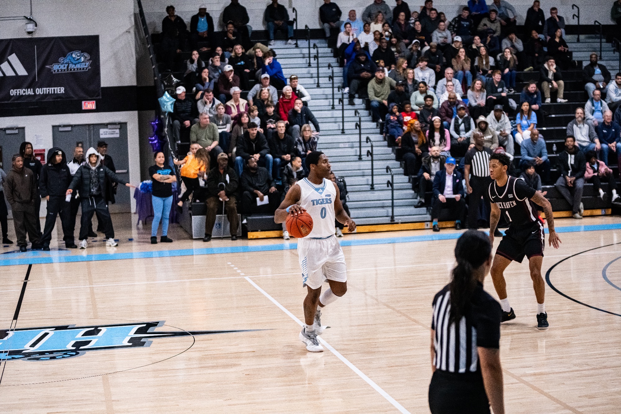 RJ Delahaye dribbles in front of a defender, just above halfcourt