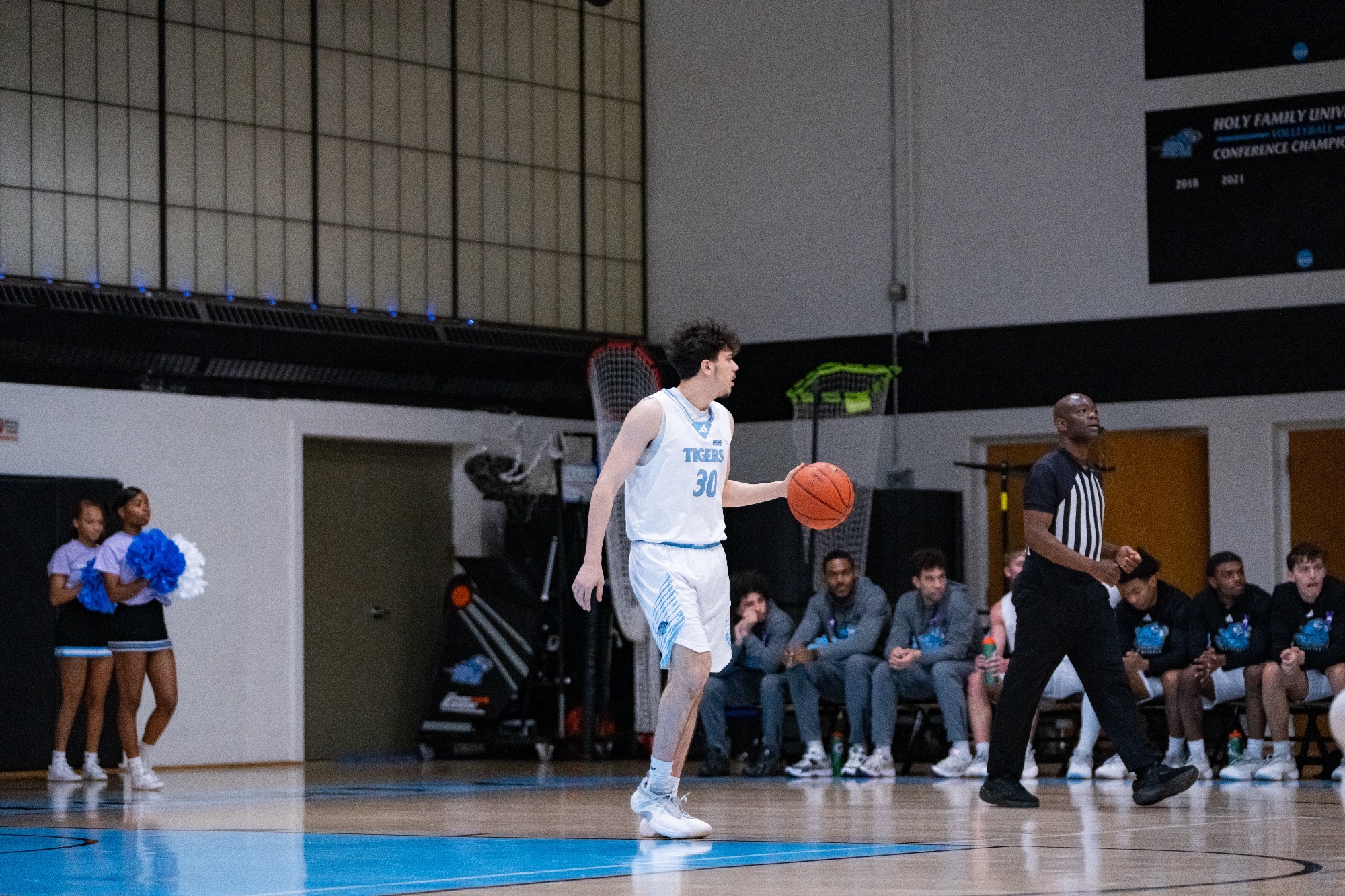 AJ Cortes dribbles the ball, looking towards the bench to his right