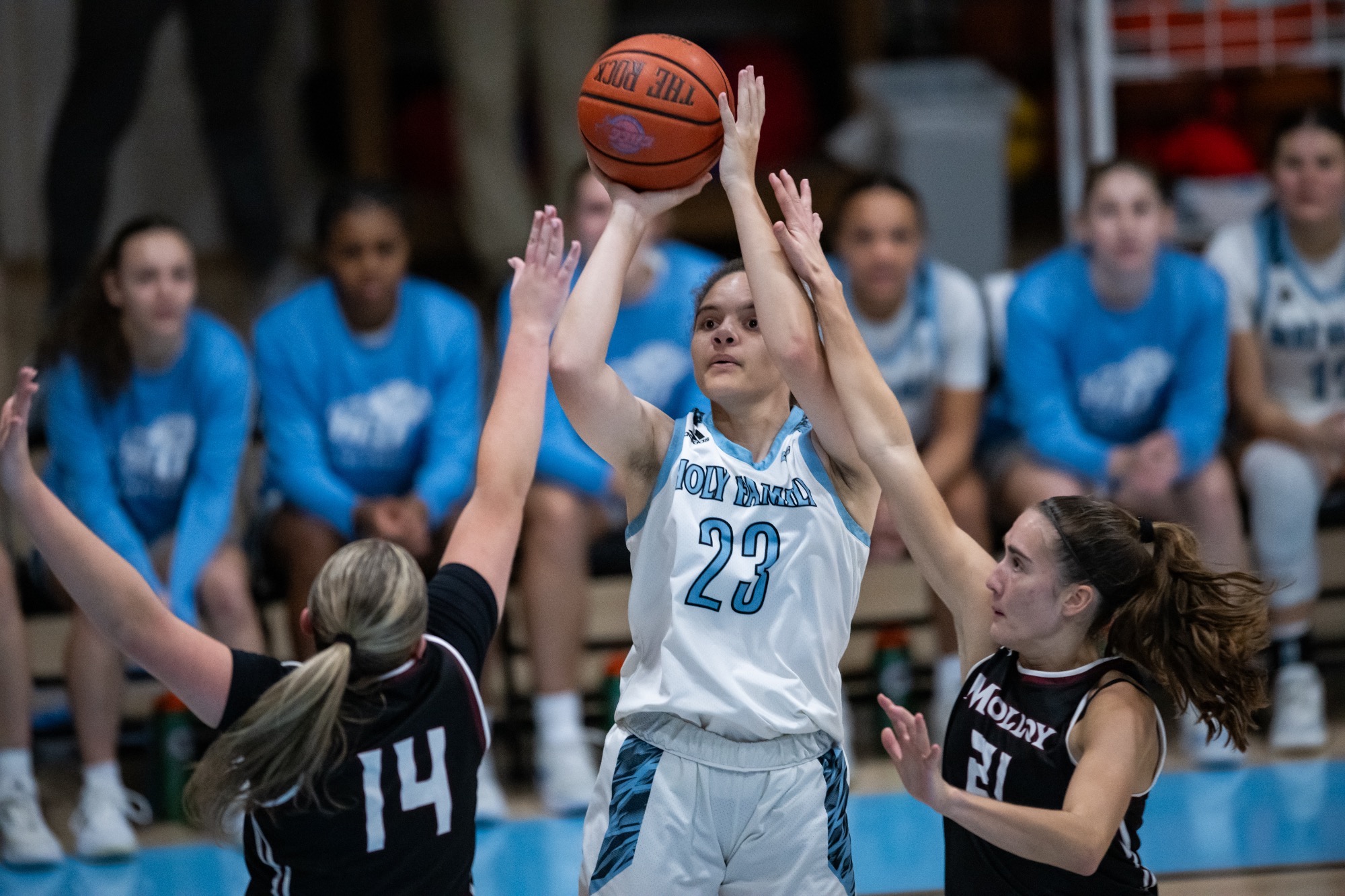 A closeup of Kaelah Carter shooting, two defenders contesting with her hand up
