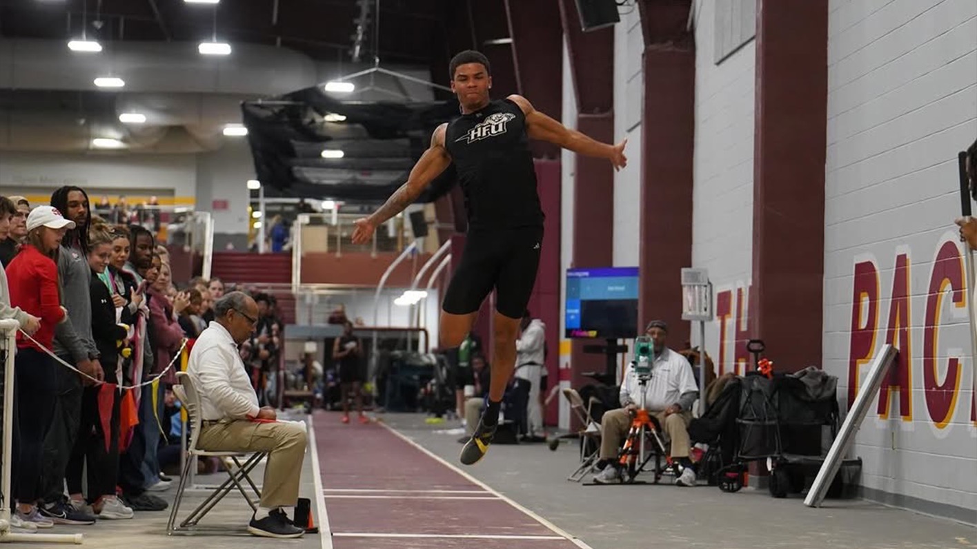 Desi Stroud in the air, about to land in the sand pit following a jump 