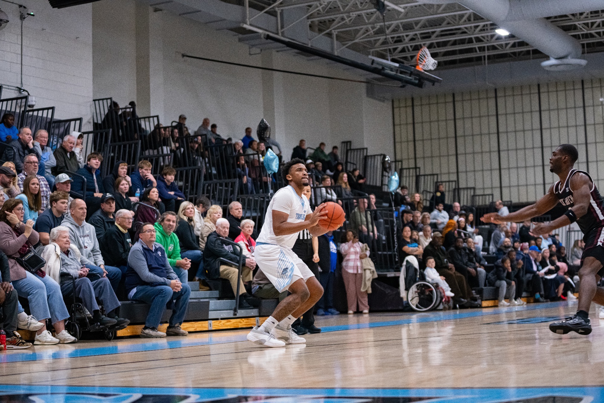Omarion Jett about to shoot a 3-pointer from the left win, the crowd behind him