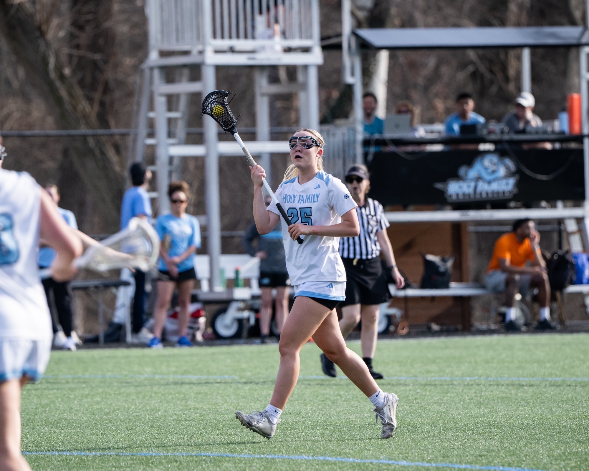 Jaime Gugger running with the ball in her stick, which is up above her head