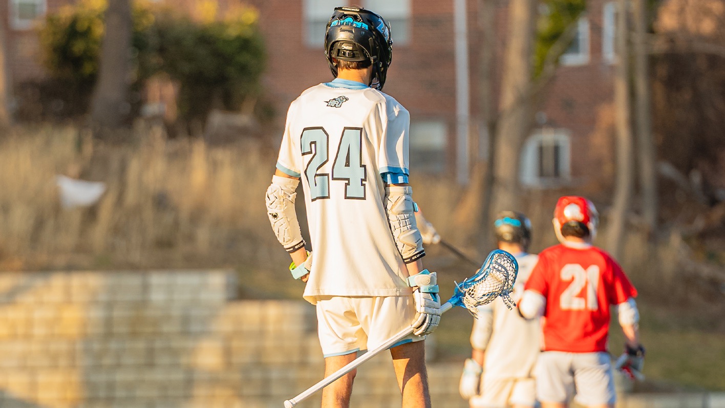 A photo of James Bienia, from behind, holding his stick in his right hand