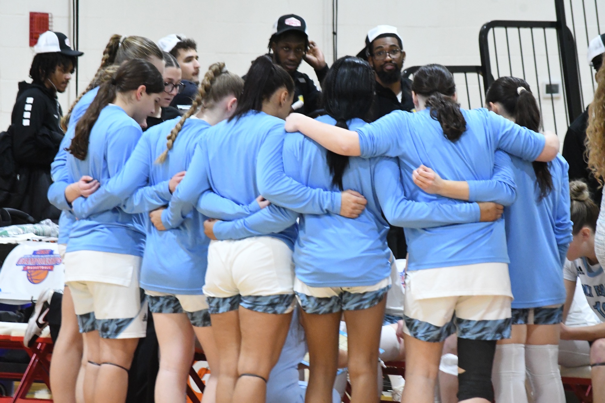 The Holy Family Women's Basketball Team huddling around the bench during the 2026 CACC Women's Basketball Championship Game