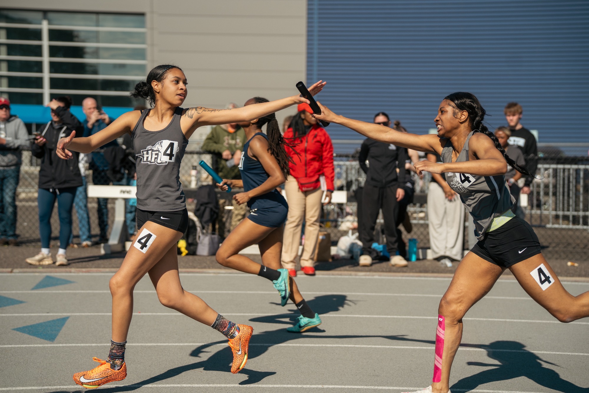 Two members of the HFU Women's Relay Team exchange a baton