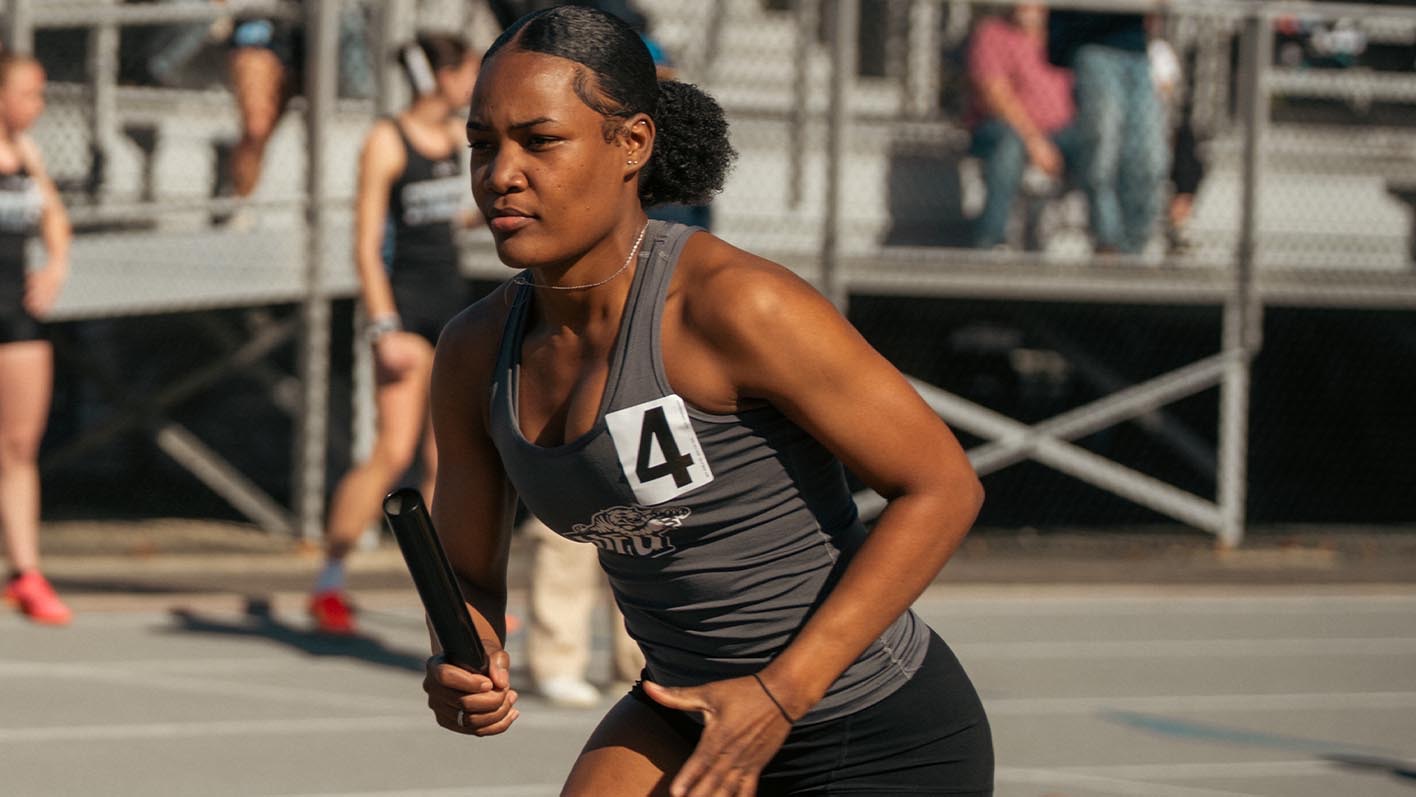 A closeup of Ocelia Jones running with a baton in her hand