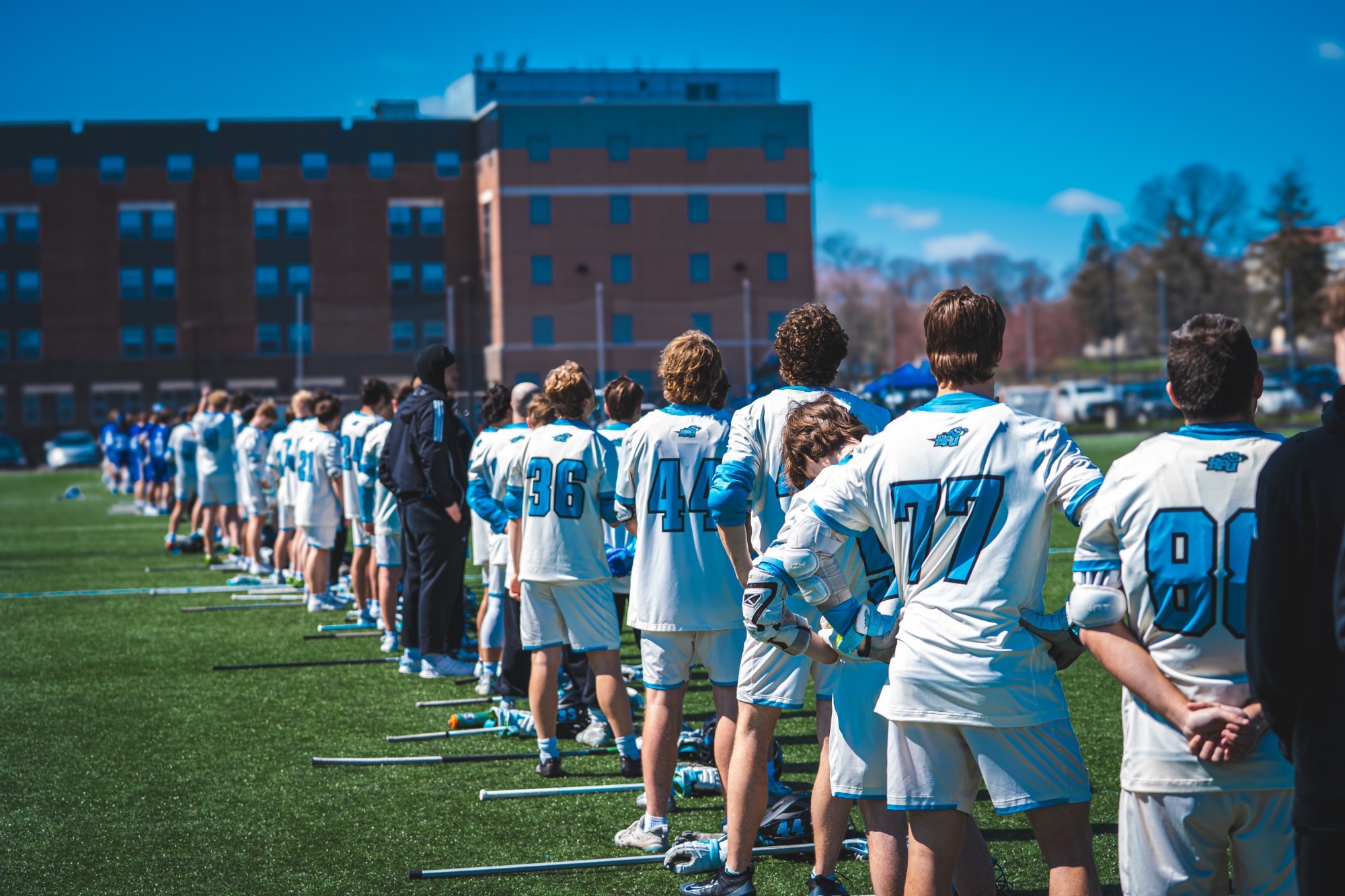 A picture from behind the 2026 HFU Men's Lacrosse as they stand on the sideline during the national anthem