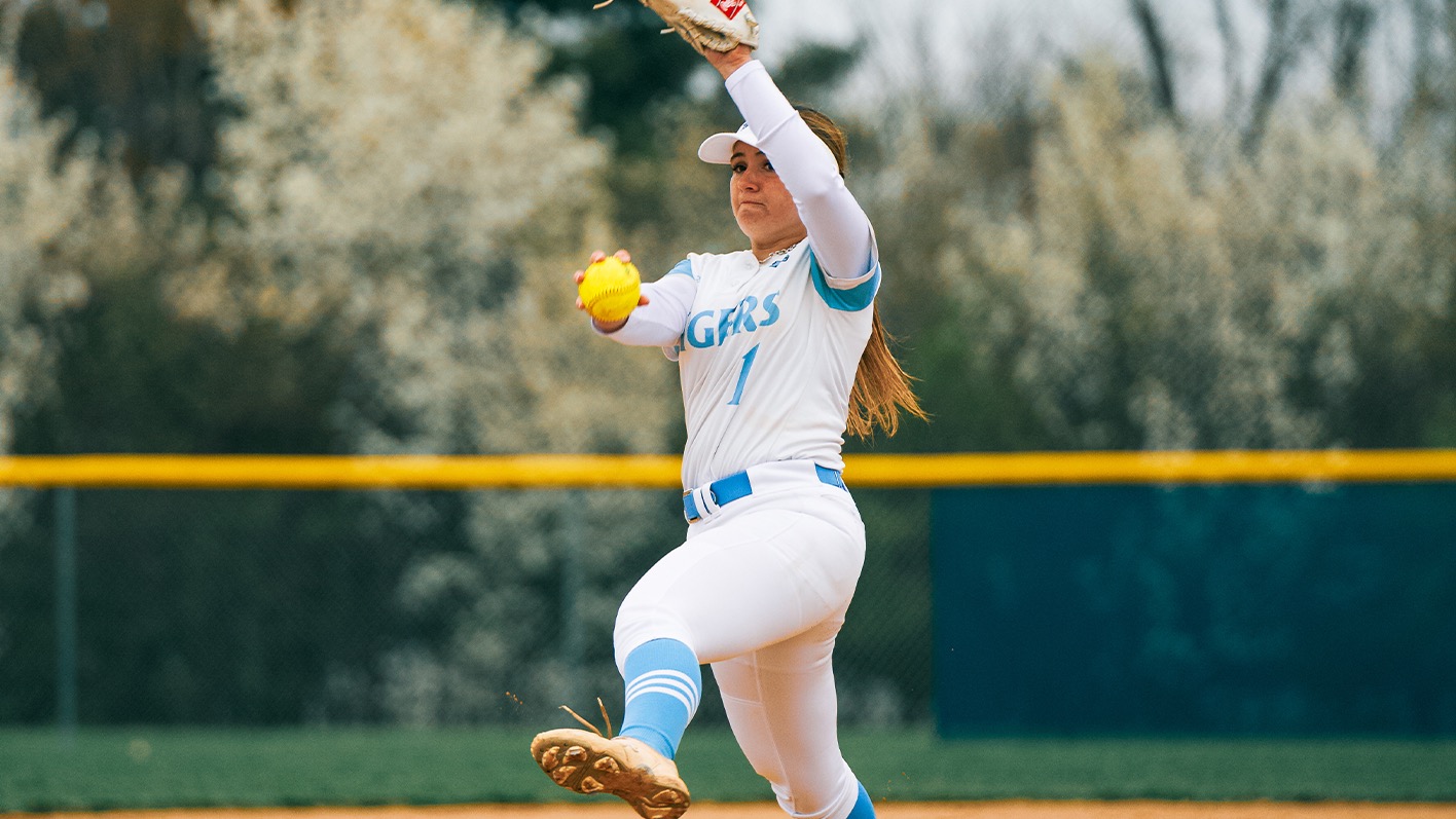 Molly Moore delivering a pitch, her left leg and left hand up, ball in her right hand