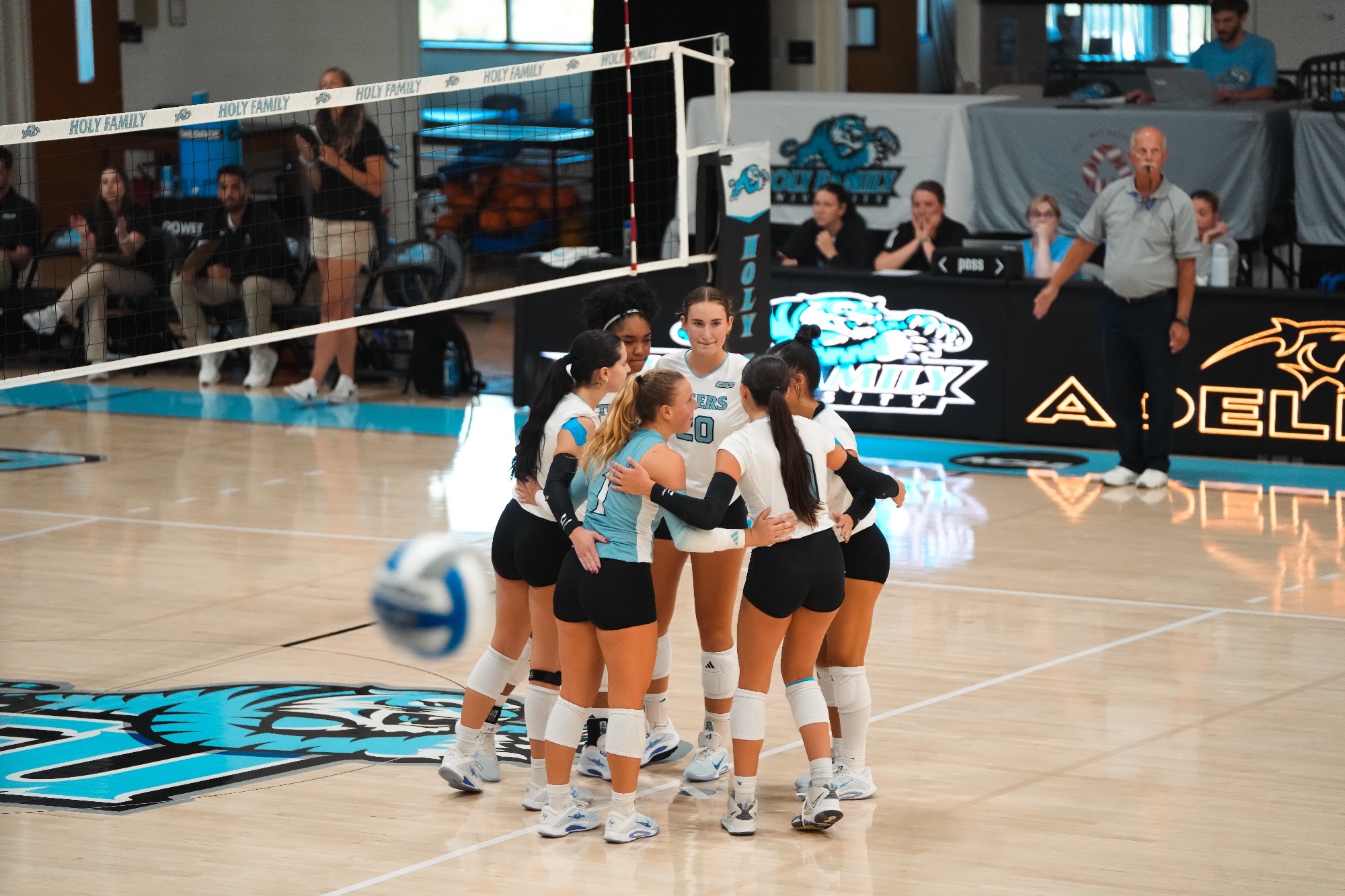 The HFU Volleyball Team huddles together on the court