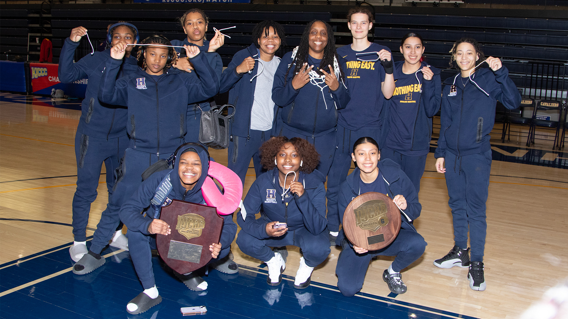 The 2024-25 Highland Women's Basketball team celebrates with their trophies and pieces of the net following a 53-42 win over Allen County on Saturday.