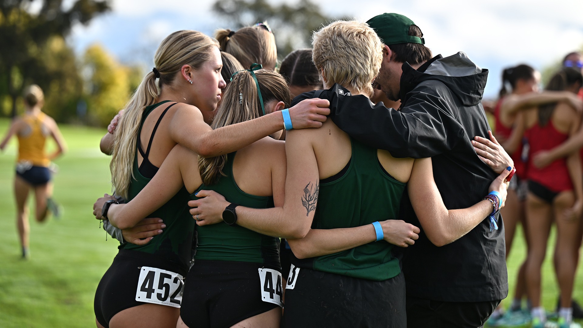 Photo of the women's cross country team in a huddle prior to a race