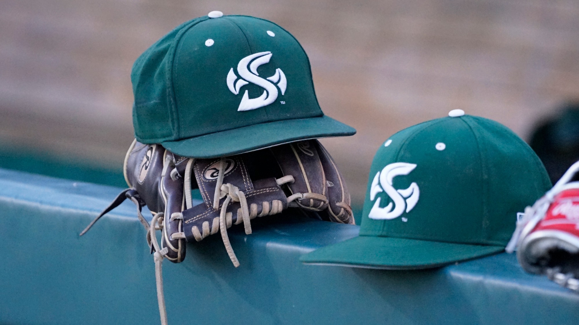 2026 BSB Sacramento State baseball hats on the dugout rail during a team practice