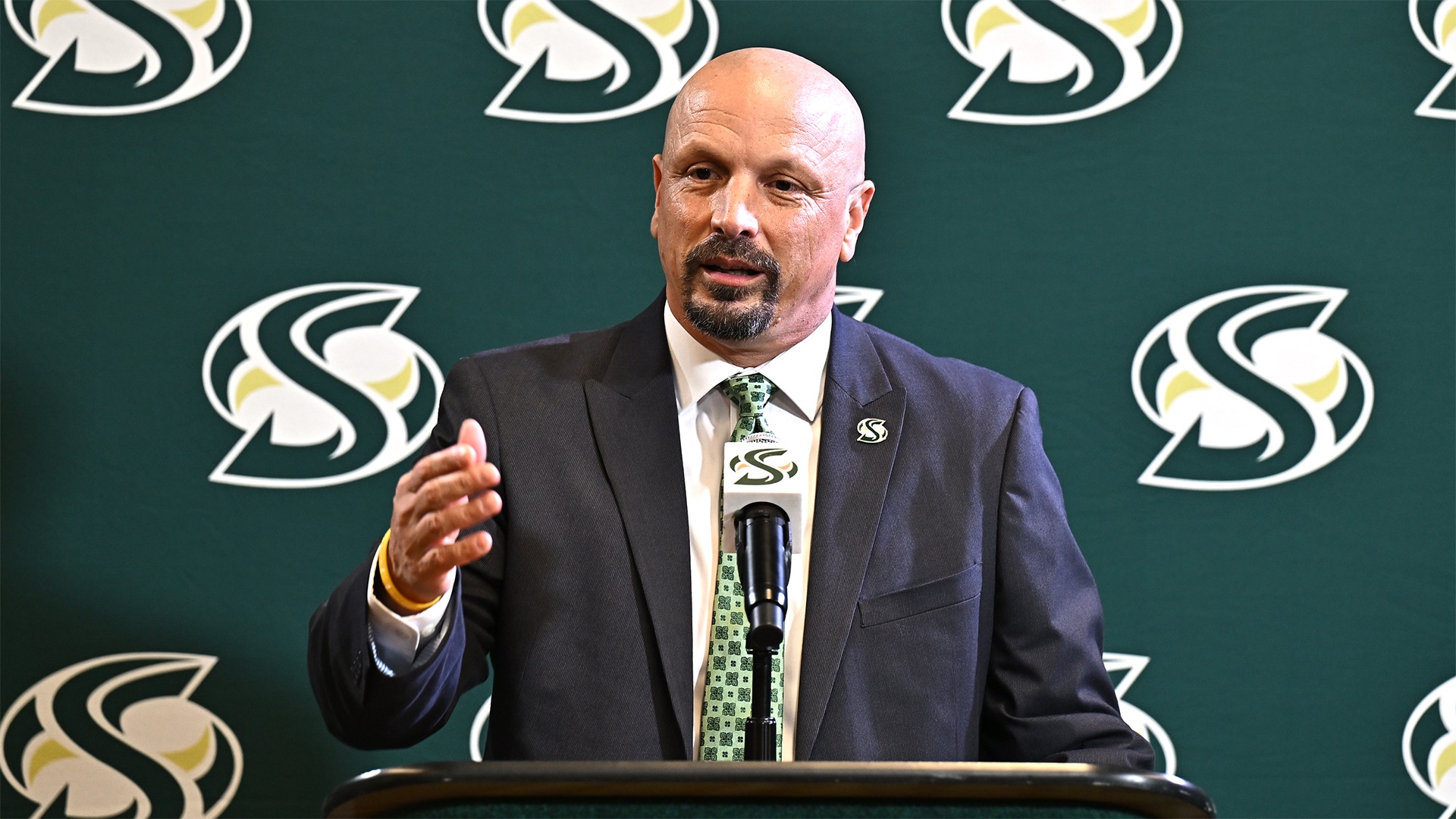 Mark Orr speaks at a podium with a Sacramento State logo backdrop behind him