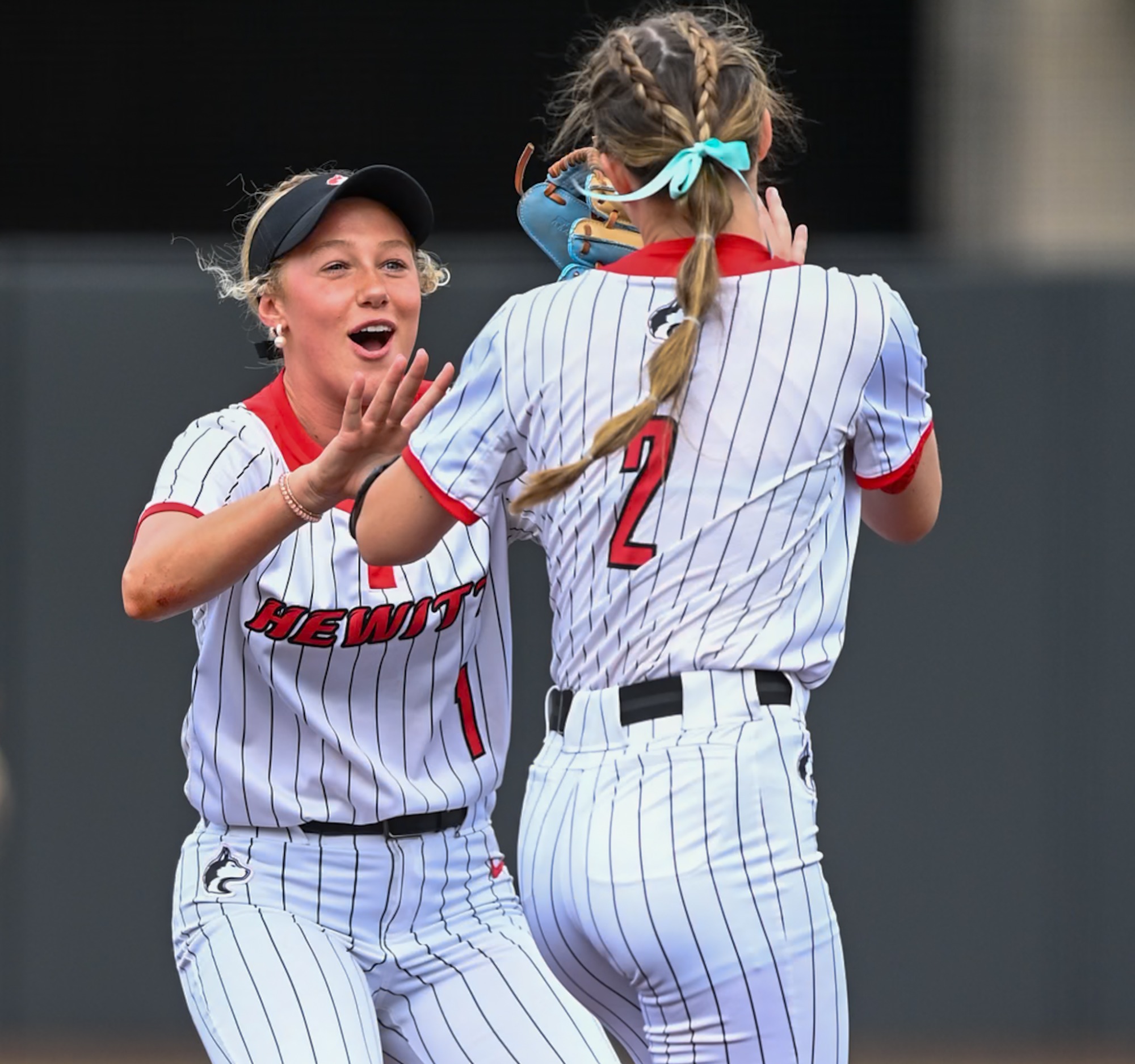 Two softball players high fiving