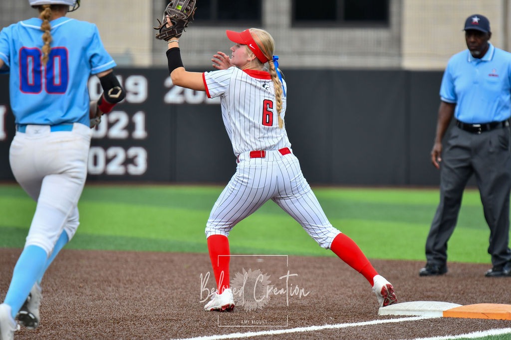 Softball player makes out at first 