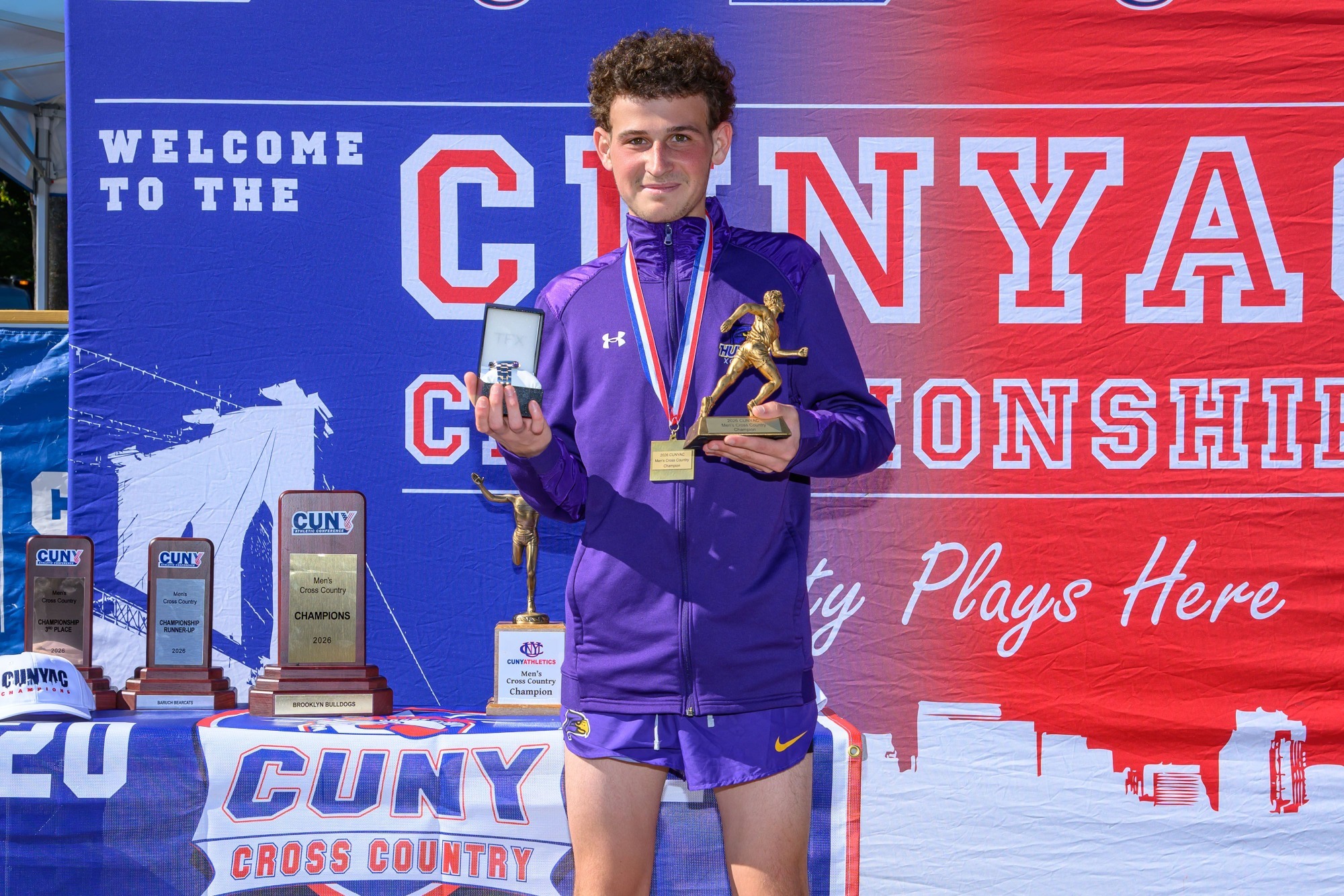 Leonardo Kaplan poses with the MVP trophy after placing first at the CUNYAC men's cross country championship.