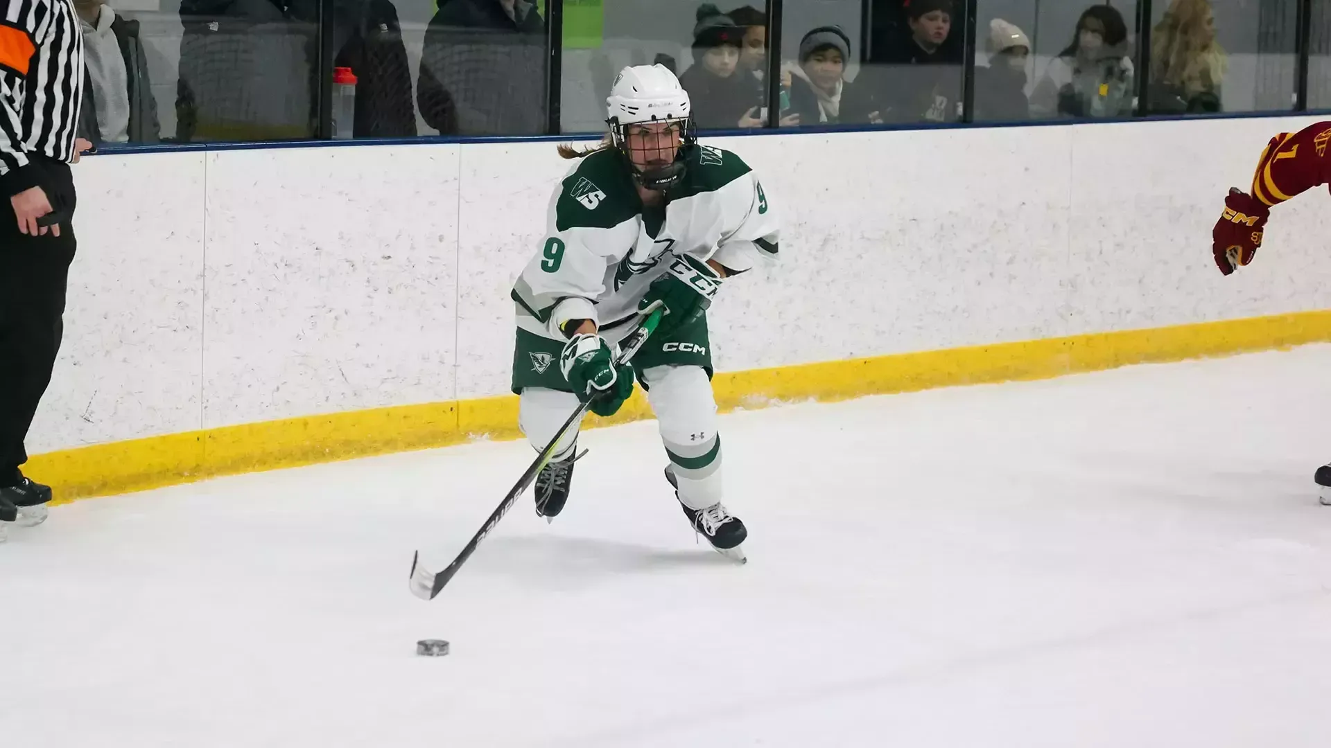 Ainsley Lonczak handles the puck by the boards 