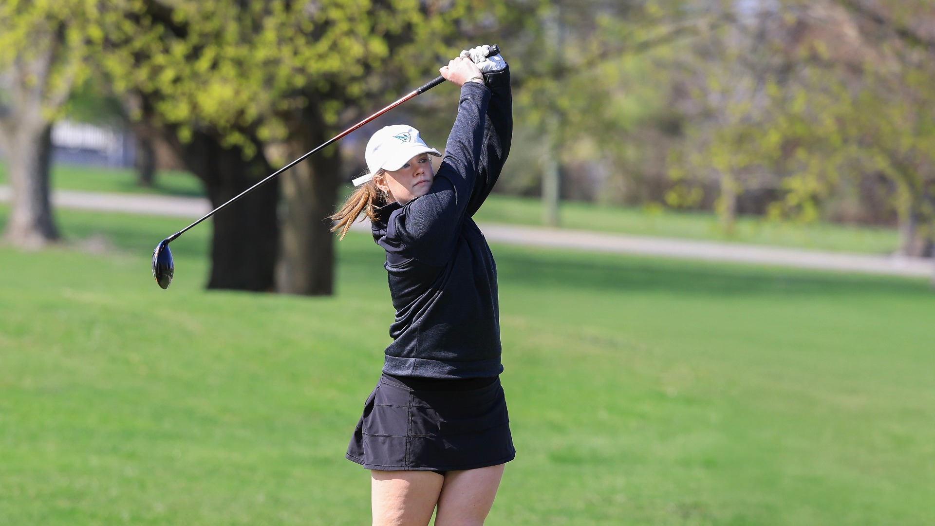 With her hands holding her club at the top of her follow through, Caroline Gannon watches her shot.