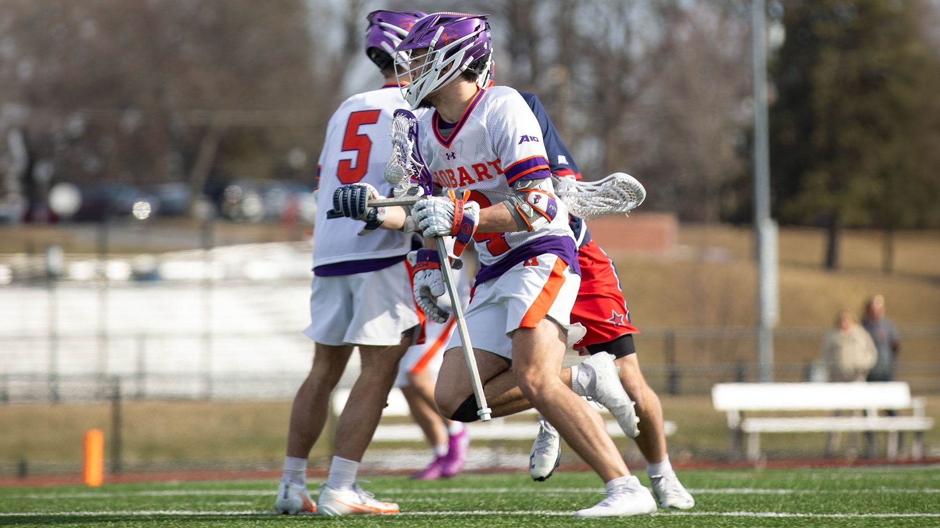 Cade Dino craddles the ball past a defender and a teammate. 