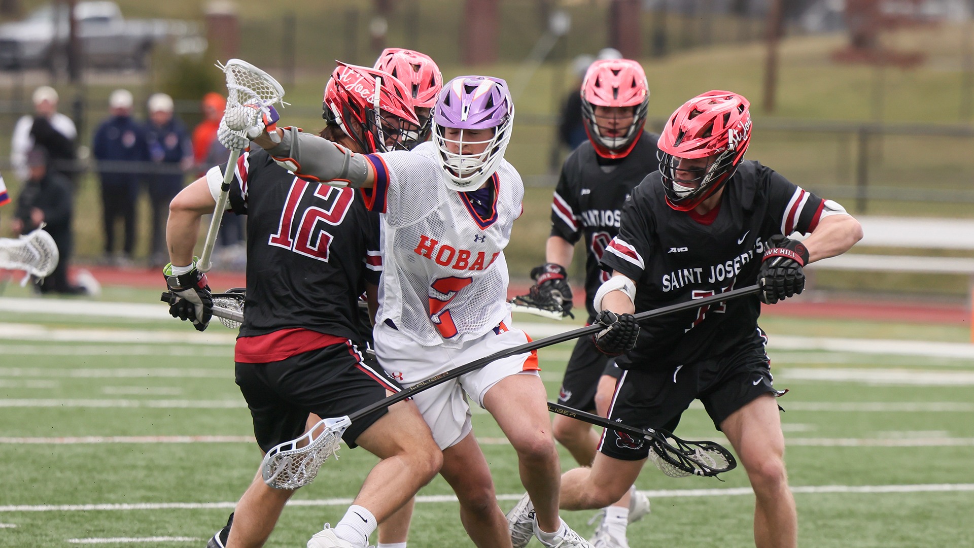 Slade Engstrom manages to protect his crosse and the ball while being checked by two SJU defensemen.