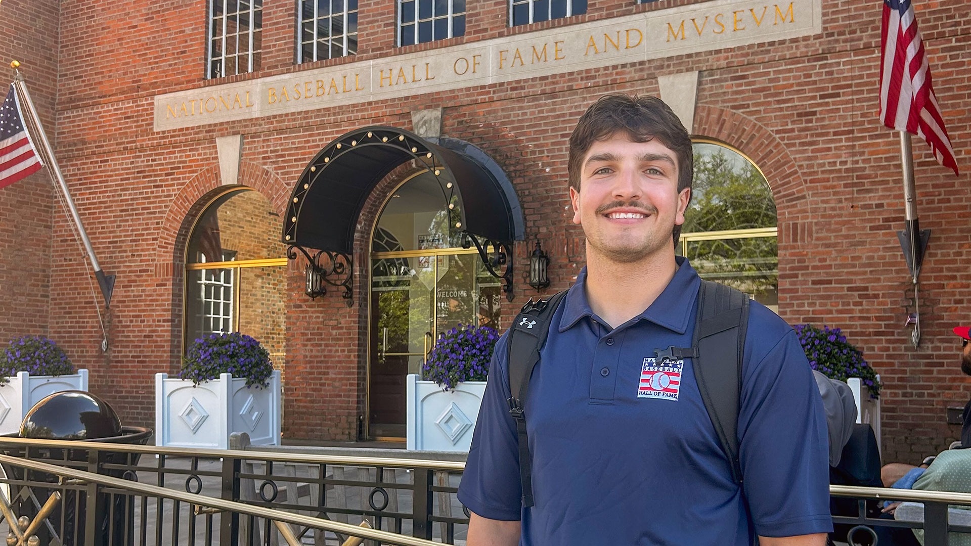 Sam Oestreicher stands outside the entrance to the National Baseball Hall of Fame.