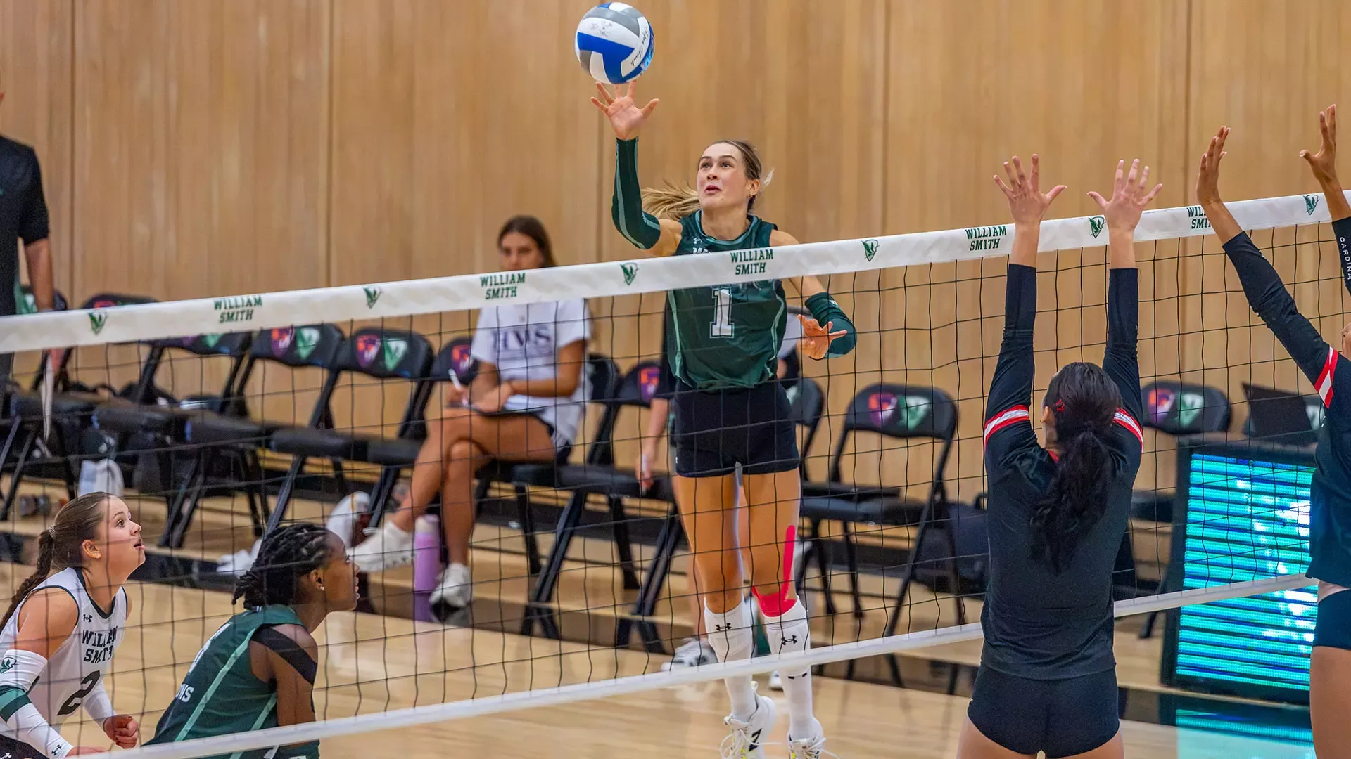 Cassidy Breuer tips the ball back over the net with one hand 