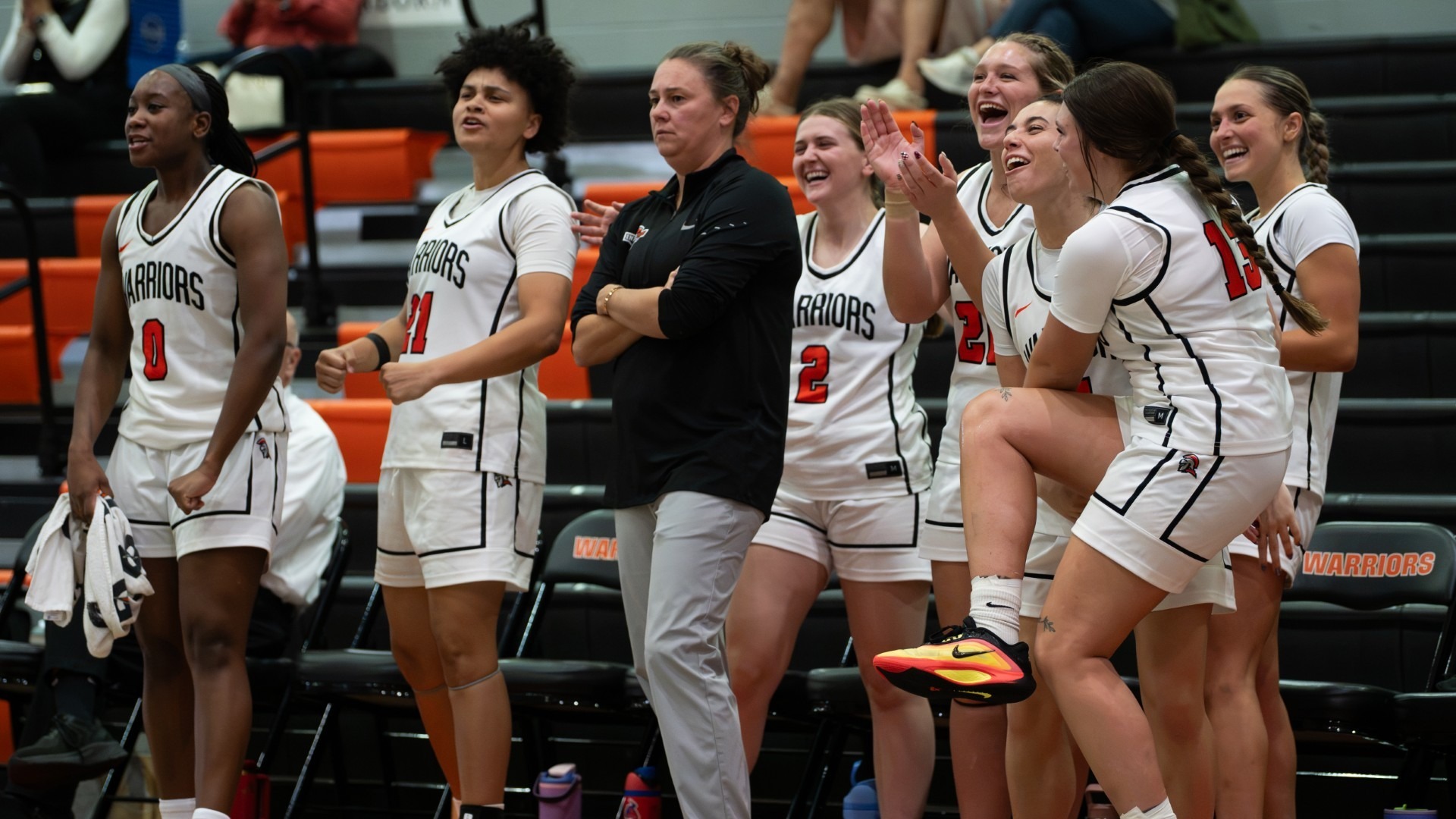 women's basketball team celebrating behind coach biggs