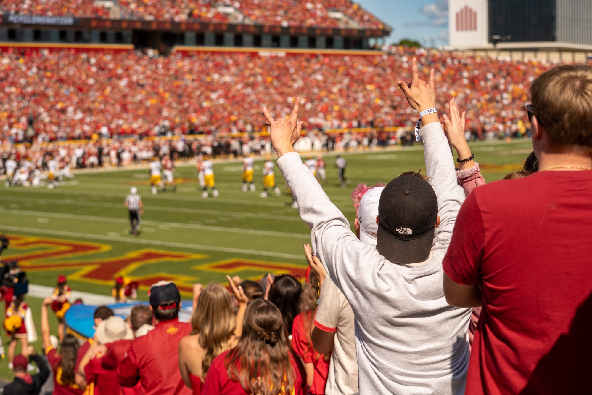 Students with arms raised watching the game from the Jack Trice Stadium student section
