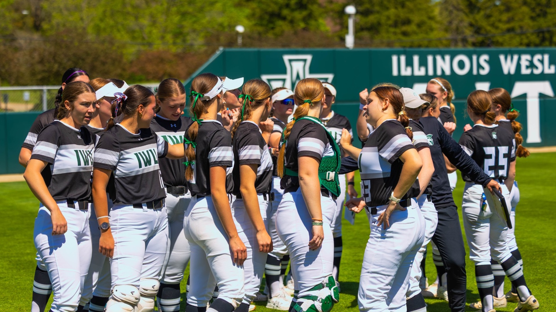 Softball huddling in between games vs Carroll