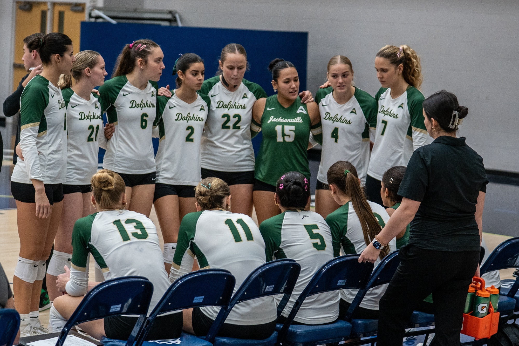 The Jacksonville volleyball team huddles on the sideline during a timeout in their match against Queens.