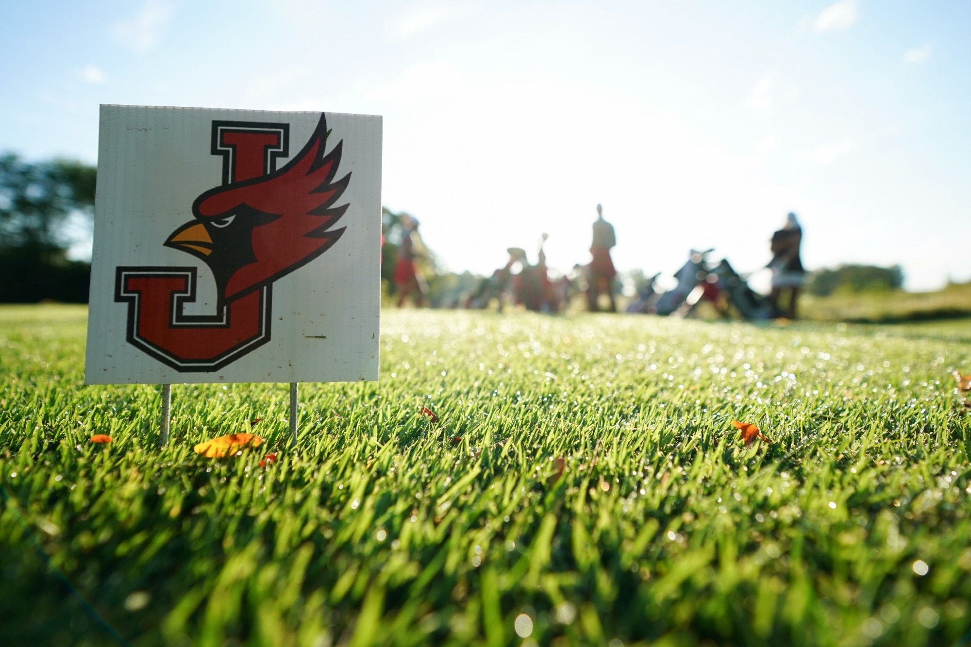 white sign with J-bird logo on golf course green