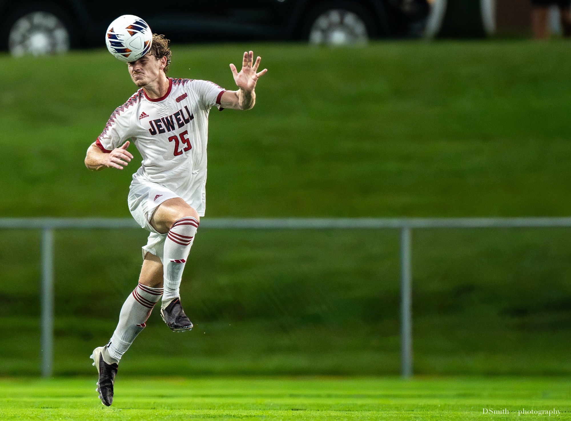 Dax Wilkinson heads the ball in the air jumping in a white Jewell jersey 