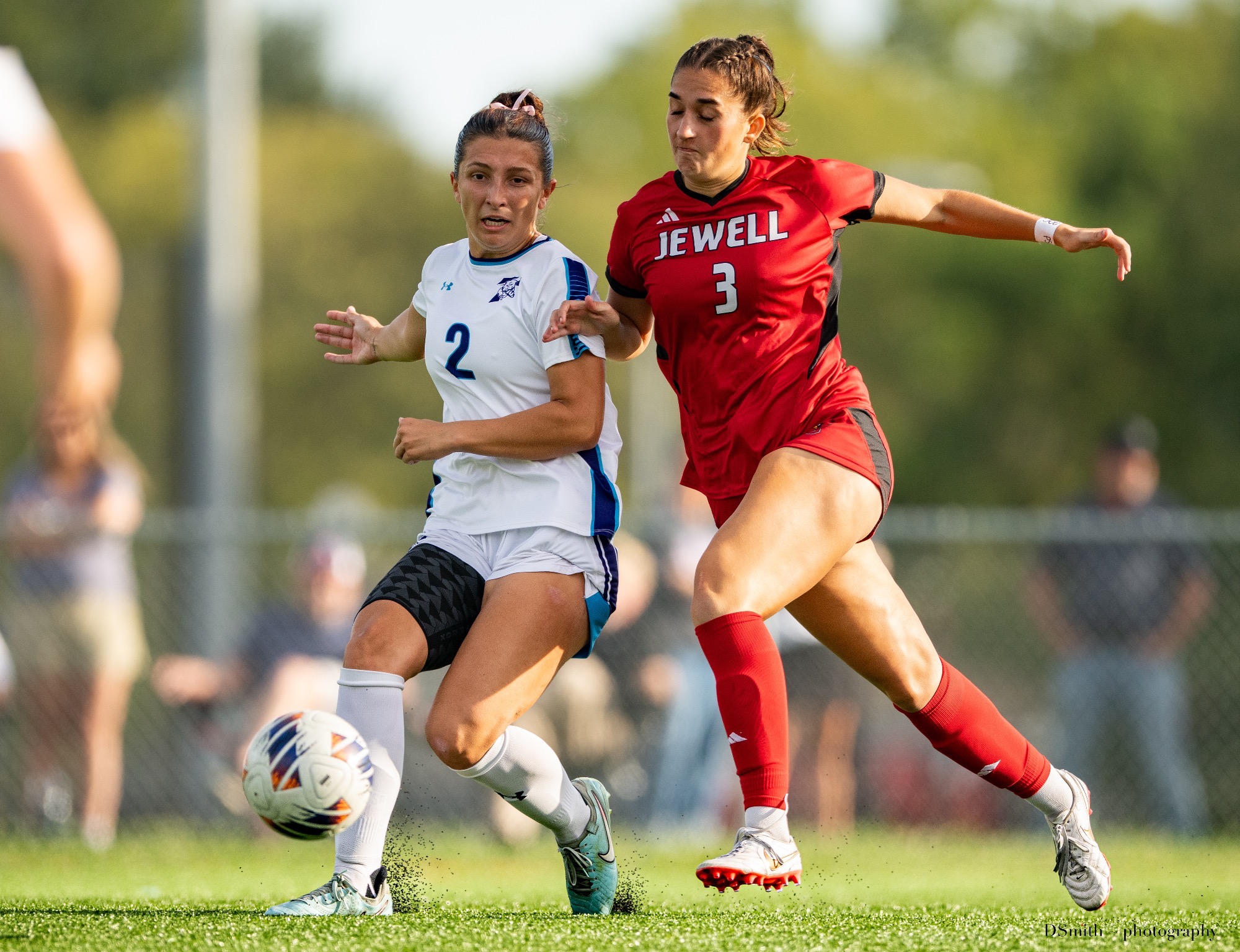 Jessica Baker tries to battle past a defender with the ball in a breakaway, wearing a red Jewell soccer jersey.
