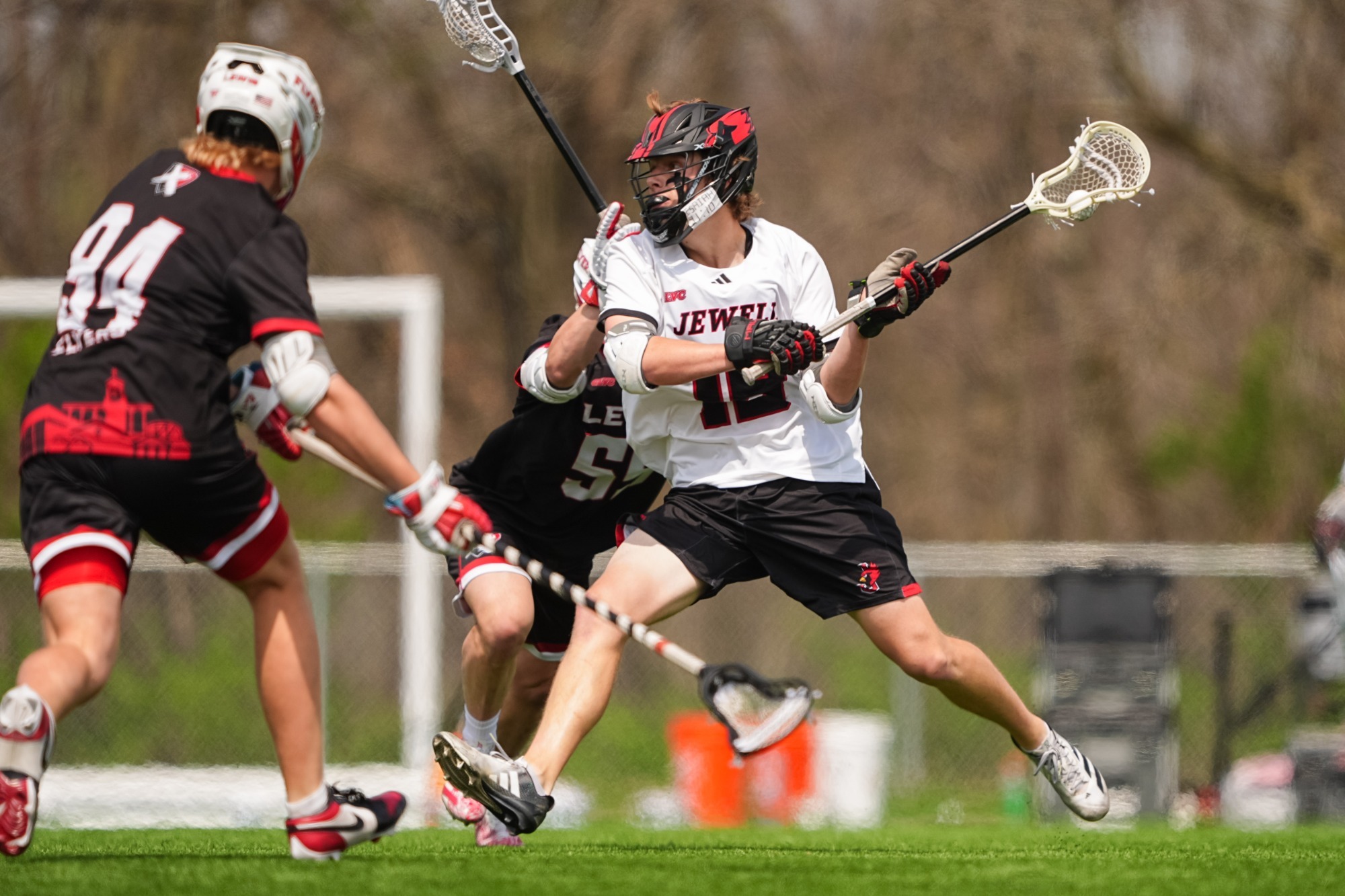 Brenner Mitts shooting lacrosse ball wearing white jersey and black helmet