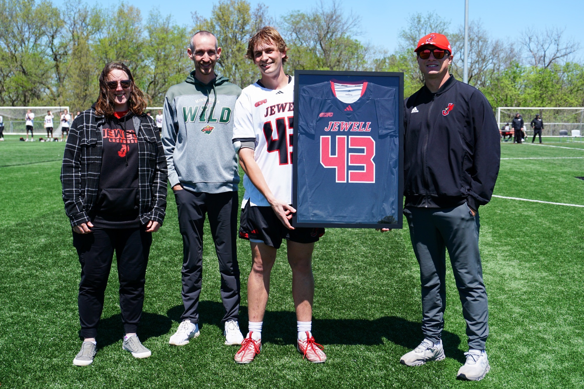 Cade Snider holding framed jersey with parents and coach