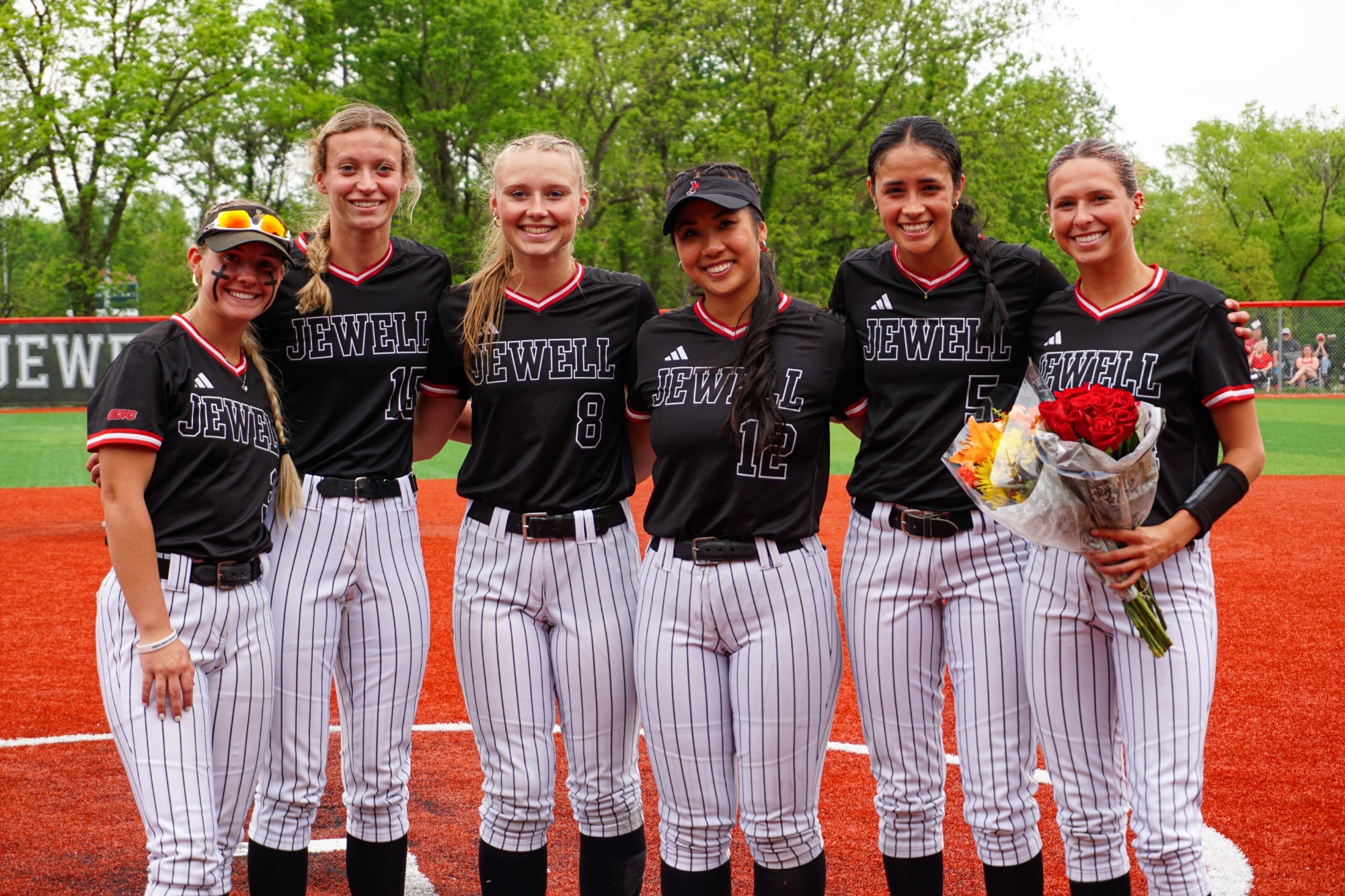 Six softball players in black uniforms with arms around each other