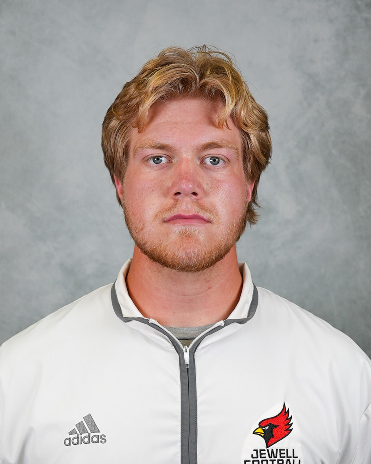 Headshot of William Jewell football coach Andrew Bontrager wearing a white Jewell Football pullover in front of a gray background