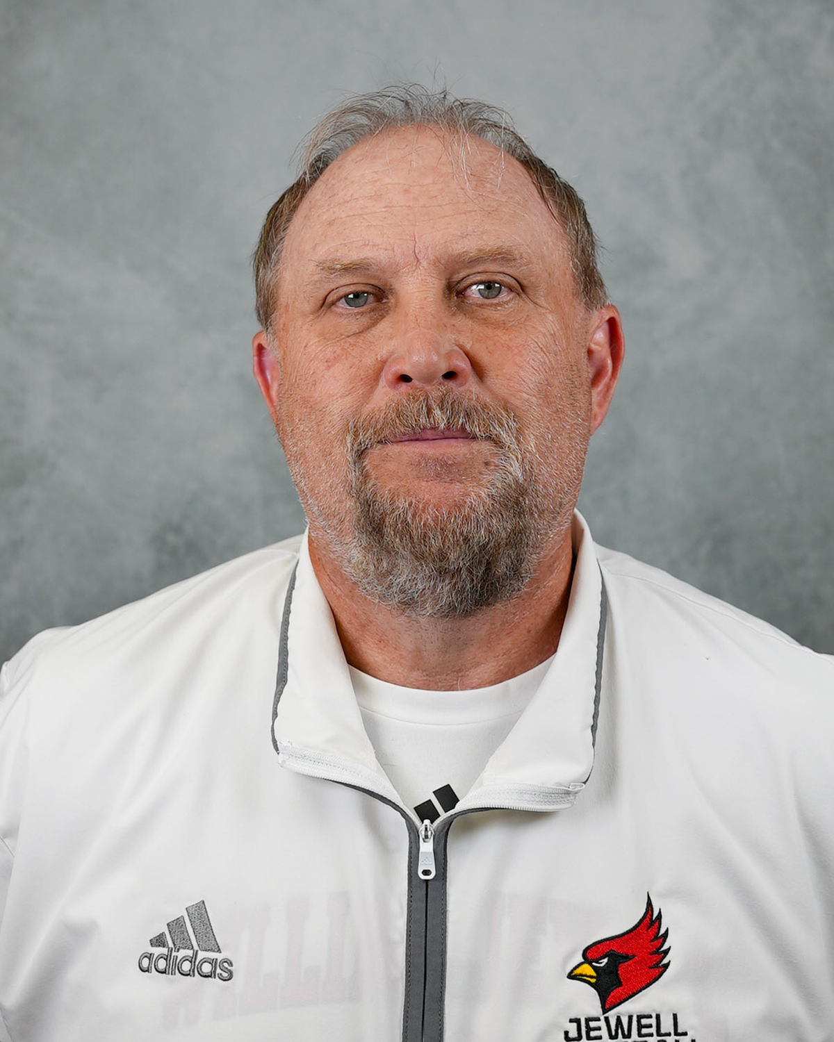 Headshot of William Jewell football coach Damon Fishback wearing a white Jewell Football pullover in front of a gray background