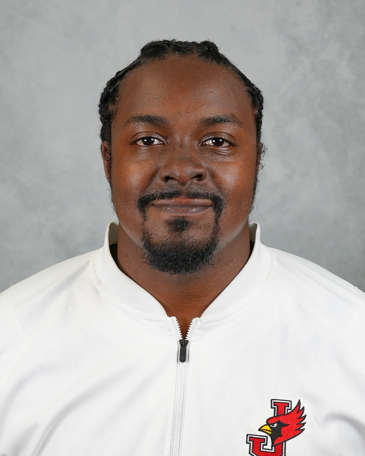 Headshot of William Jewell football coach Tore' Hurst wearing a white Jewell Football pullover in front of a gray background