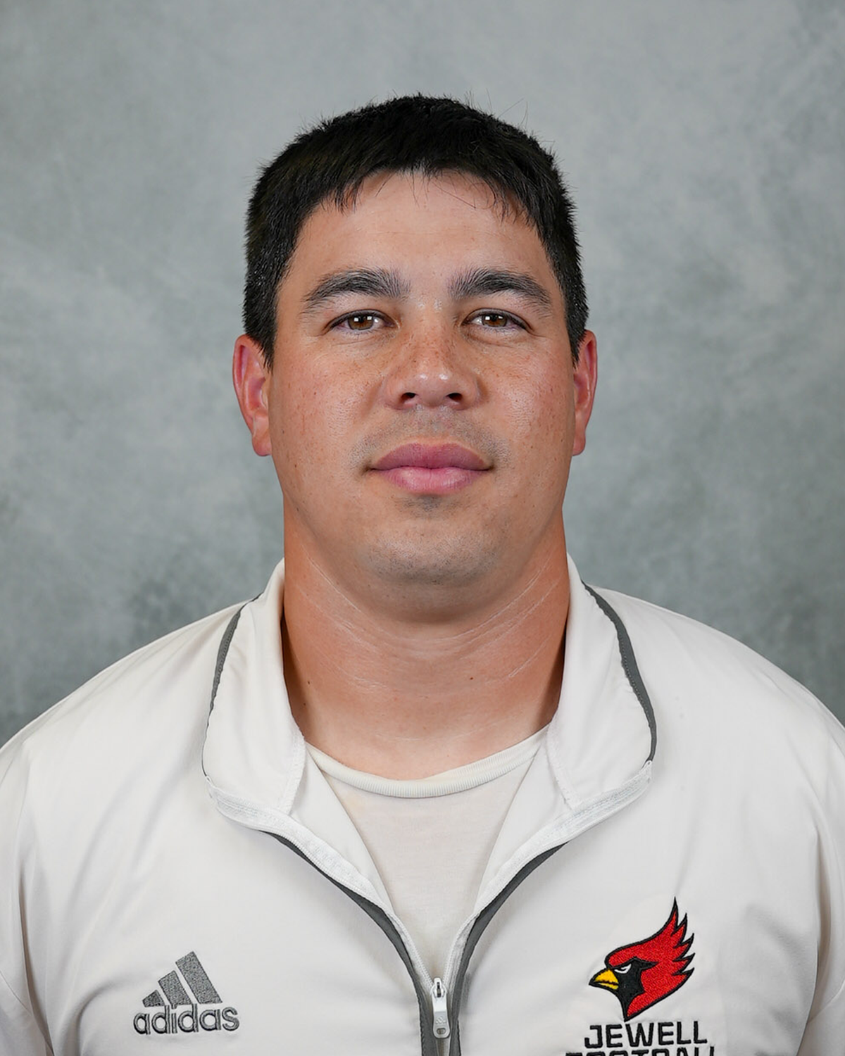 Headshot of William Jewell football coach Steve Wright wearing a white Jewell Football pullover in front of a gray background