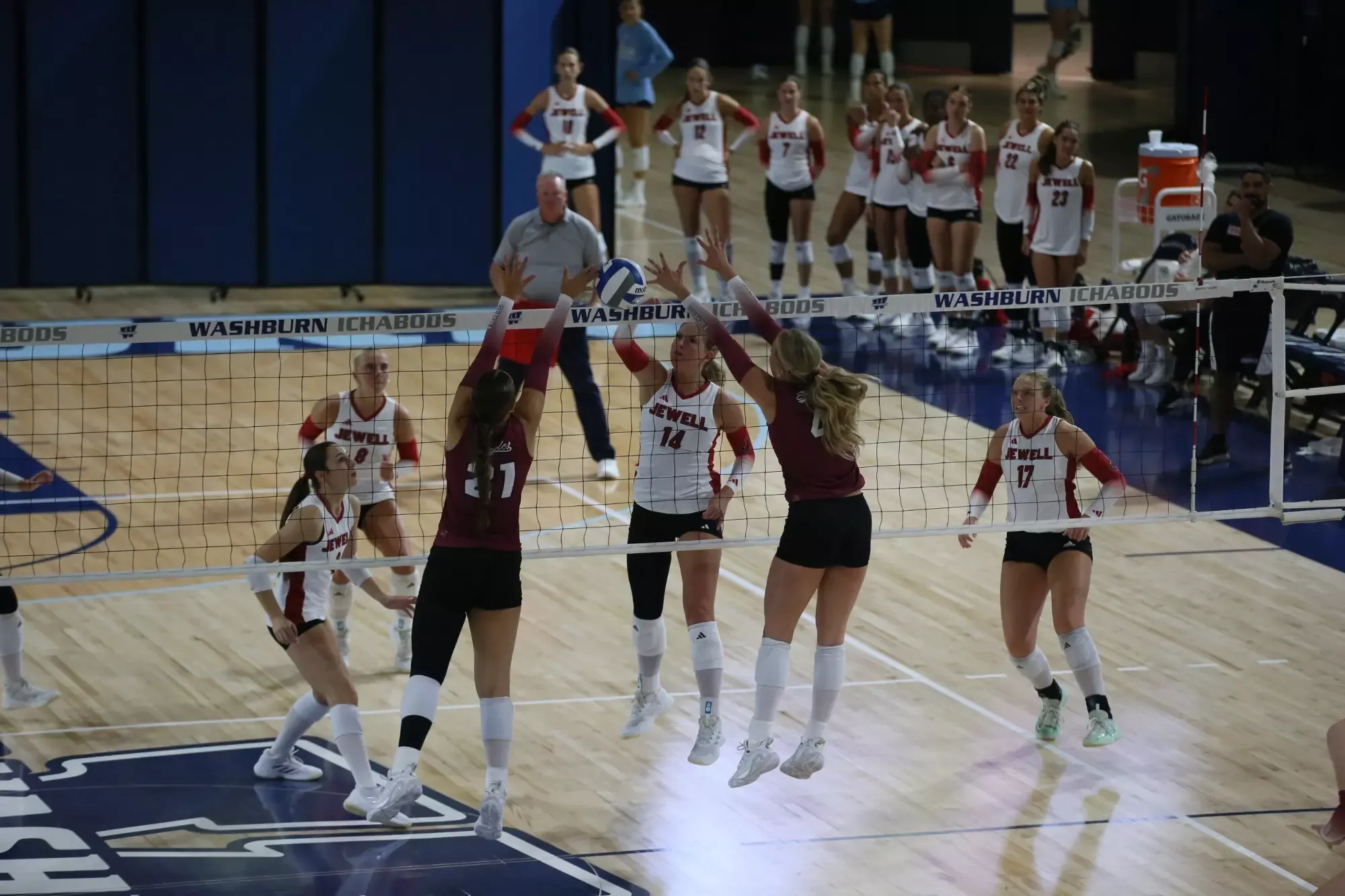 Emily Brannan jumps at the net as they attempt to hit with two blockers in front of her in a tournament at Washburn