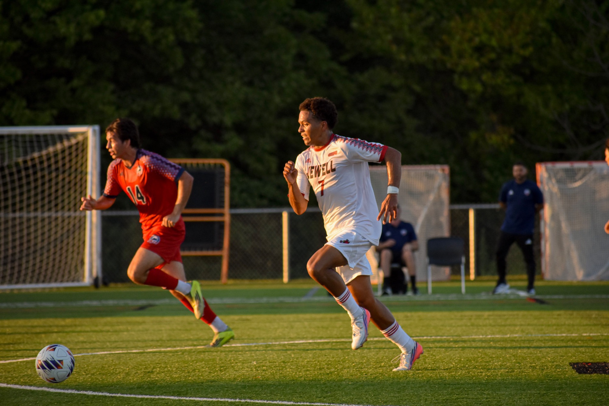 Elias Munoz runs while dribbling a soccer ball while wearing a white jersey