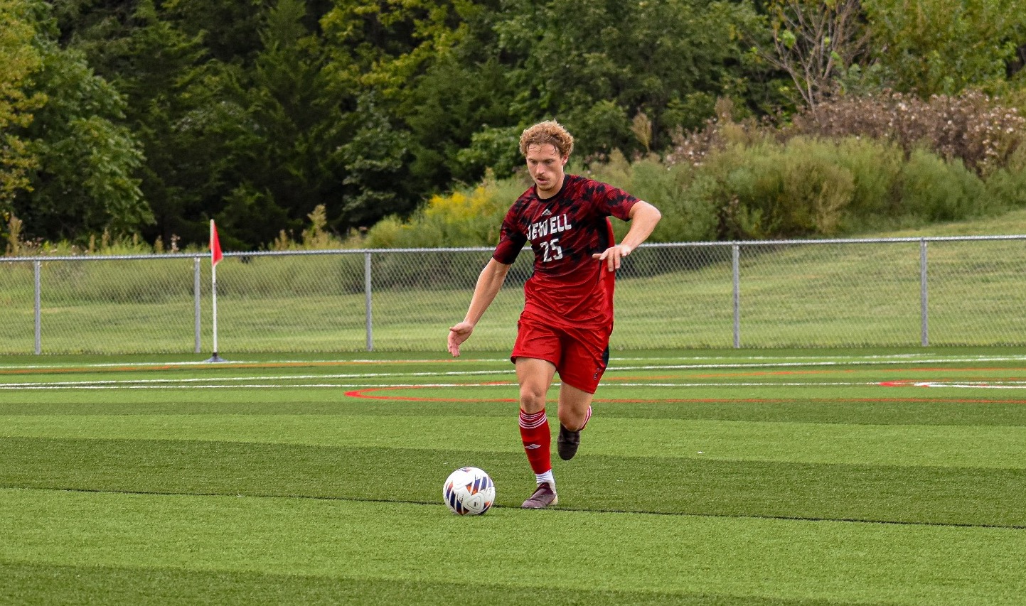 Dax Wilkinson dribbling a soccer ball while wearing a red Jewell soccer jersey 