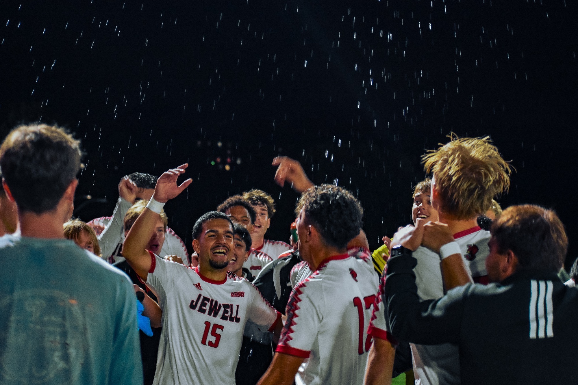Alan Sari and team celebrate with the student section after a game, water can be seen being sprayed around 